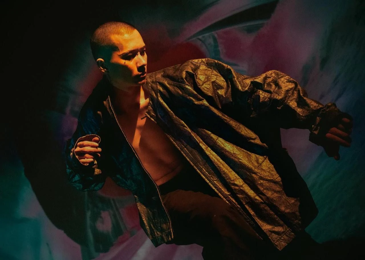 Tú Hoàng in movement on stage, lit in amber and teal